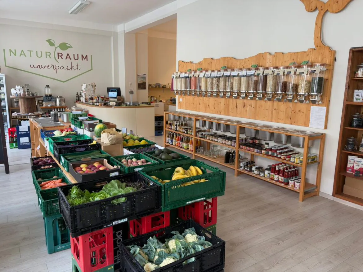 Regionale Produkte aus der Sächsischen Schweiz – Lust auf Heimat Ein Zero-Waste-Lebensmittelladen mit frischen Produkten in grĂĽnen Kisten, AbfĂĽllbehältern an einer Holzwand und Regalen mit Gläsern und Konserven. Der Laden wirkt sauber und aufgeräumt.